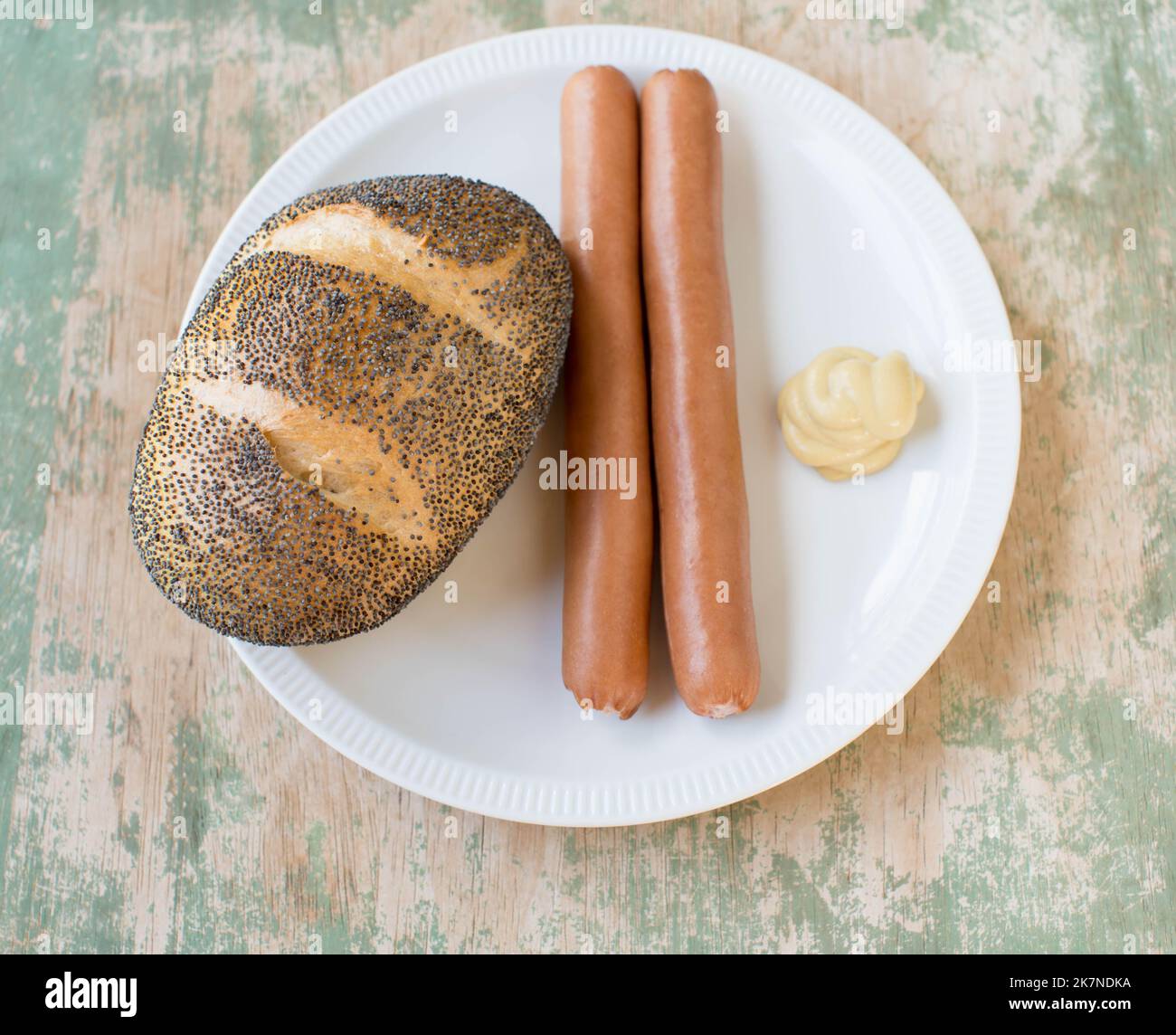 Panino di semi di papavero con salsiccia di vienna e senape su un piatto Foto Stock