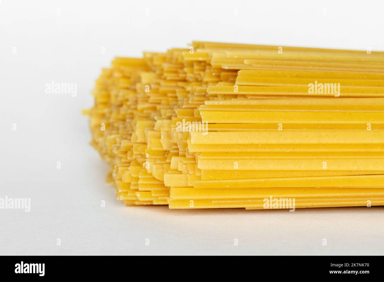 Fettuccine di durum crude su fondo bianco. Spaghetti o tagliatelle crudi. Foto Stock