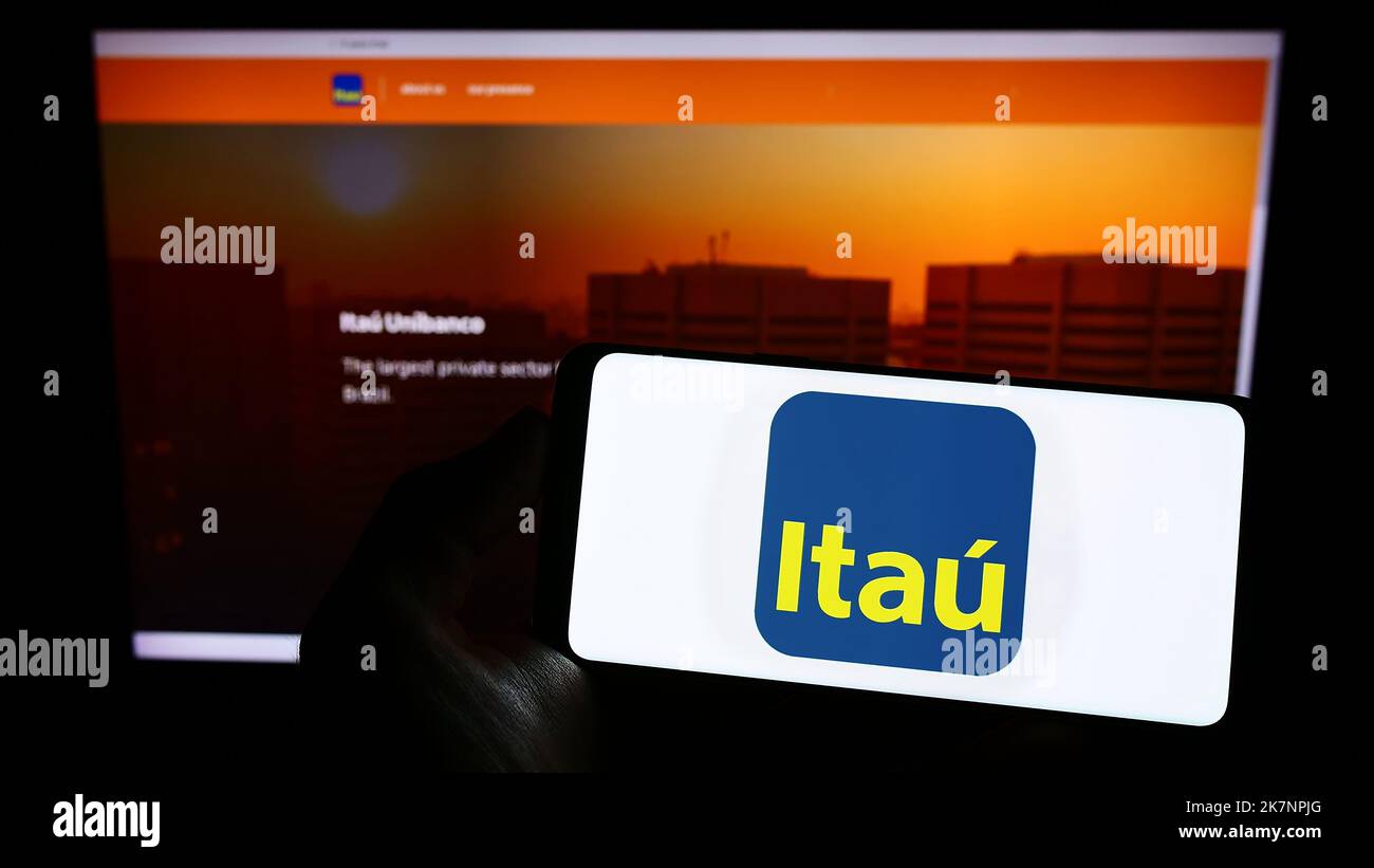 Persona che tiene uno smartphone con il logo della società brasiliana Itau Unibanco Holding S.A. sullo schermo di fronte al sito web. Messa a fuoco sul display del telefono. Foto Stock