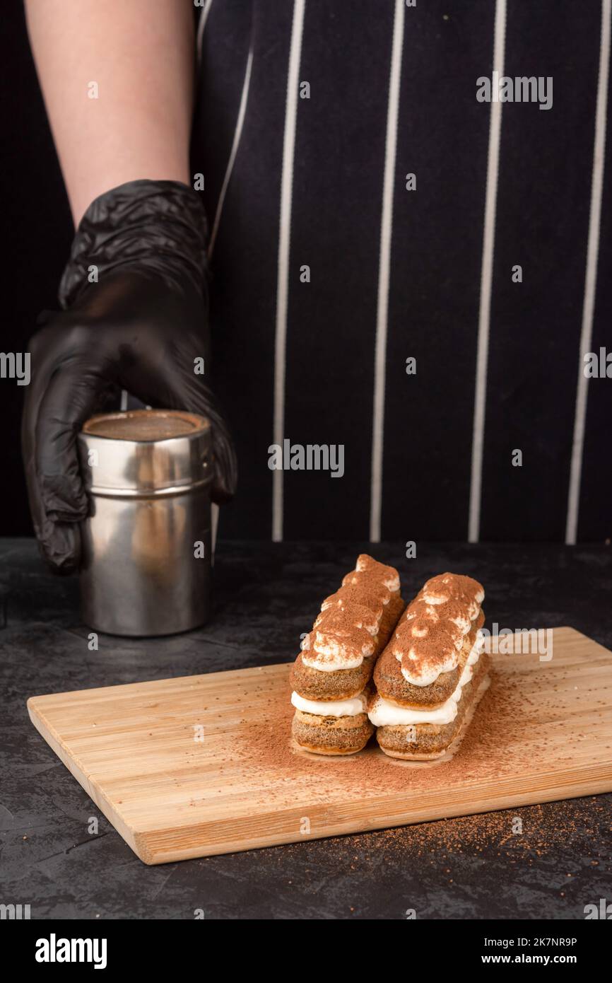 Preparazione di dolci tiramisù su sfondo scuro in una caffetteria Foto Stock