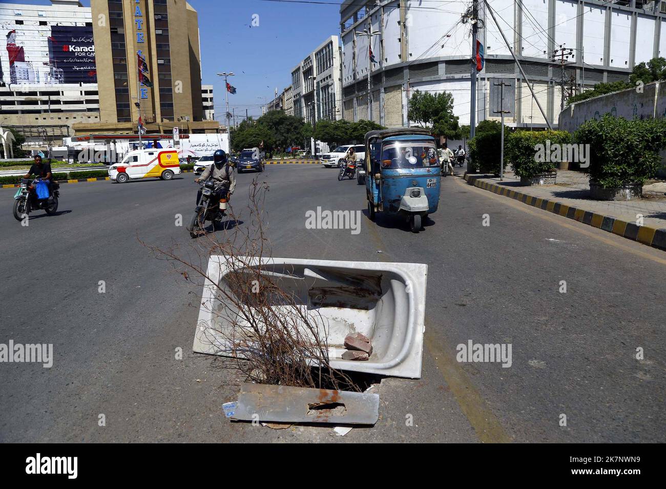 I pendolari passano nelle vicinanze di un foro principale della rete fognaria aperta che può causare incidenti specialmente nelle ore notturne, mostrando la negligenza dei reparti interessati, al di fuori dell'edificio Sindh Governor House a Karachi martedì 18 ottobre 2022. Foto Stock