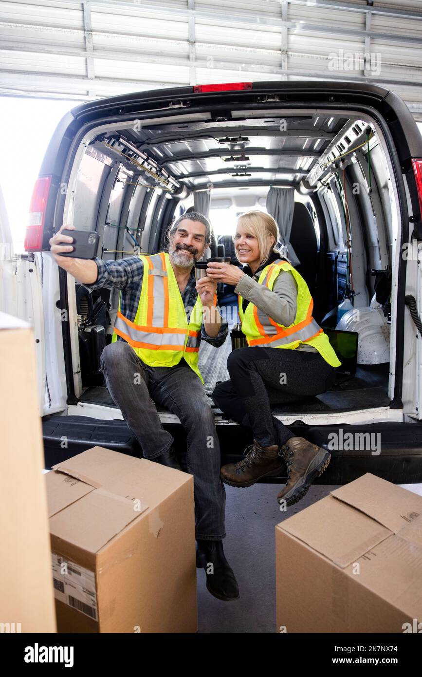 Operai felici del magazzino che prendono selfie durante la pausa caffè sul  retro del furgone Foto stock - Alamy
