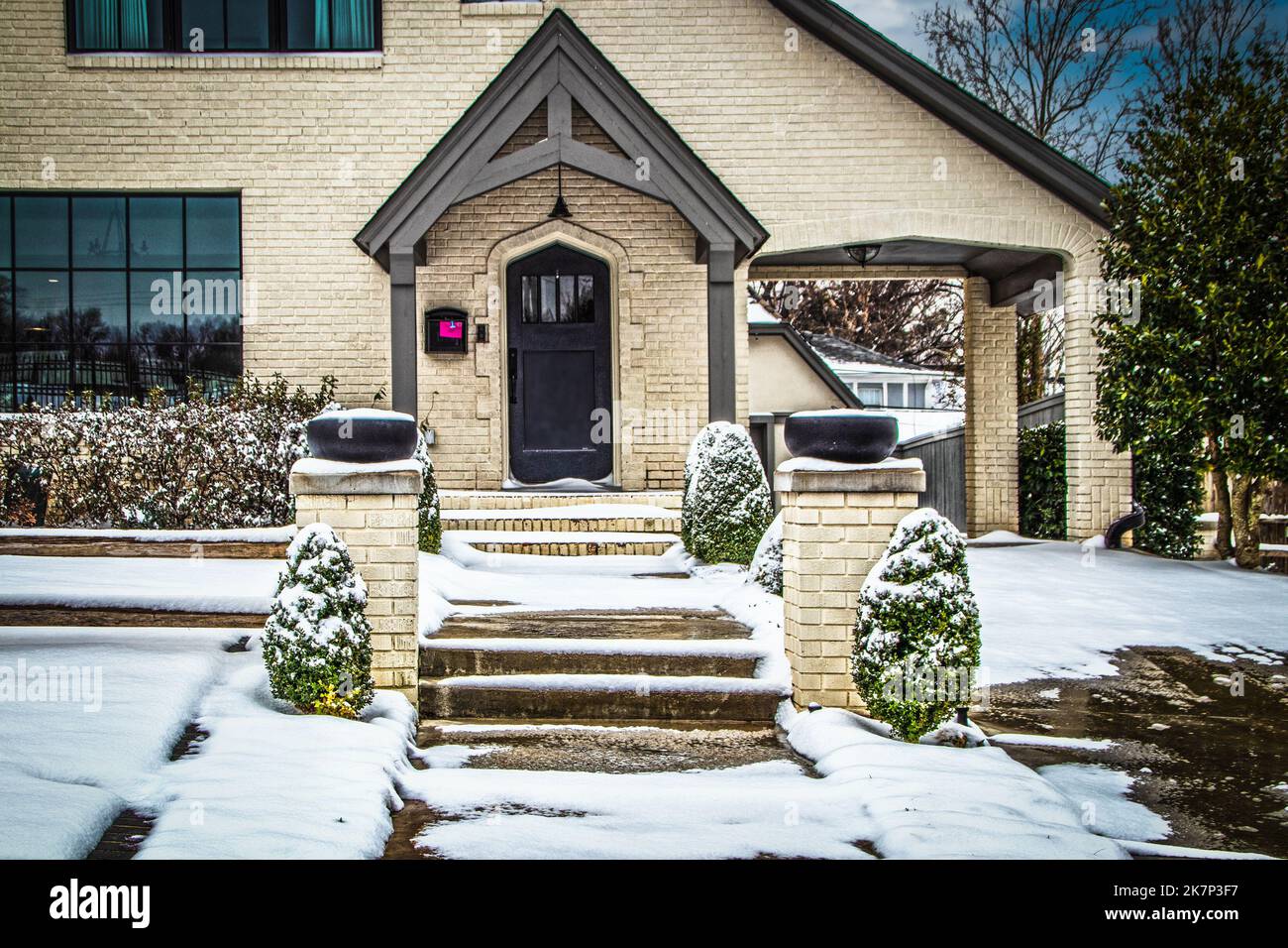 Casa in mattoni chiari nella neve - Porte Cochere e marciapiede con gradini che sono stati salati - paesaggistica e lettera rosa fissato alla cassetta postale Foto Stock