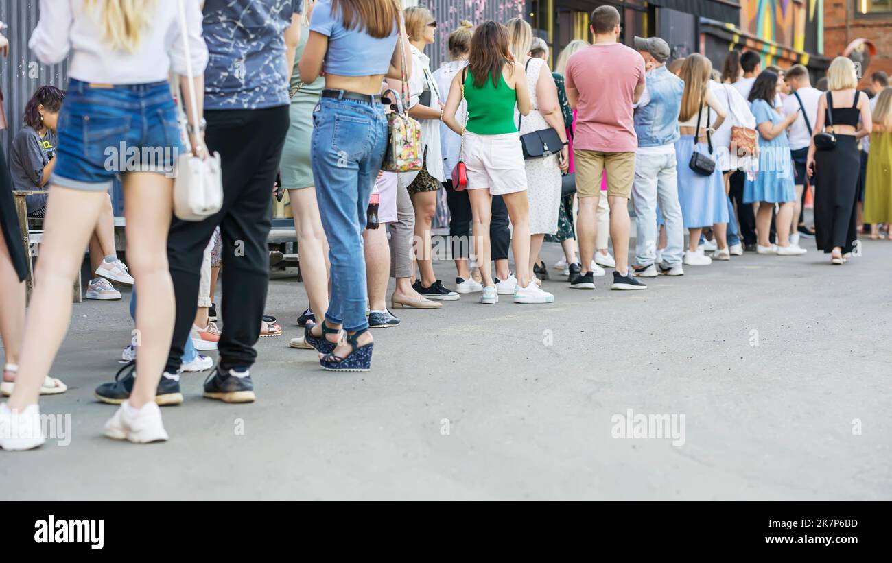 Gruppo di persone anonime accodate in fila in piedi in fila lunga, vista posteriore Foto Stock