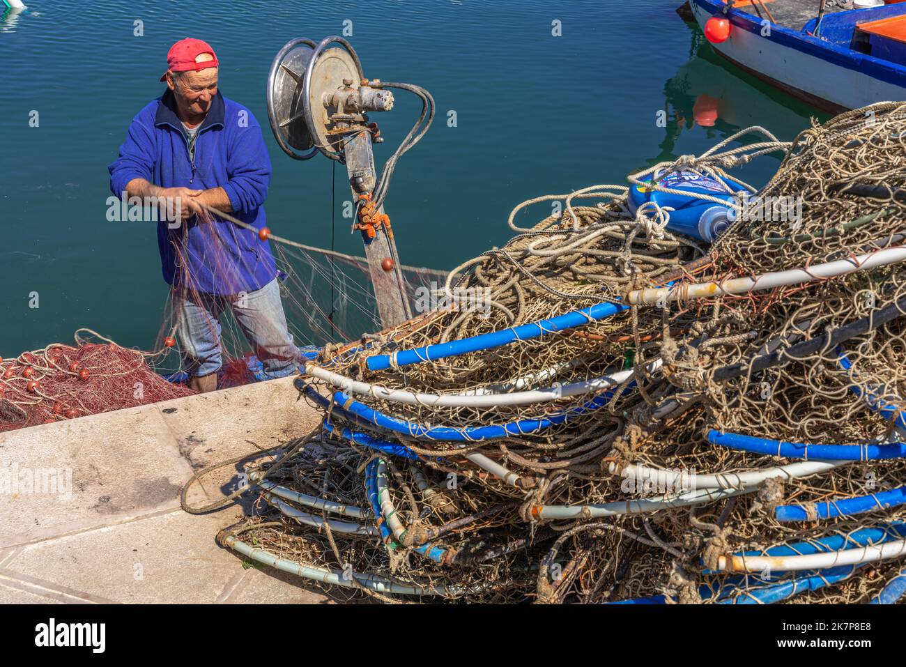 Un pescatore ripara e fissa le sue reti dopo la pesca nel Mare Adriatico. Puglia, Italia, Europa Foto Stock