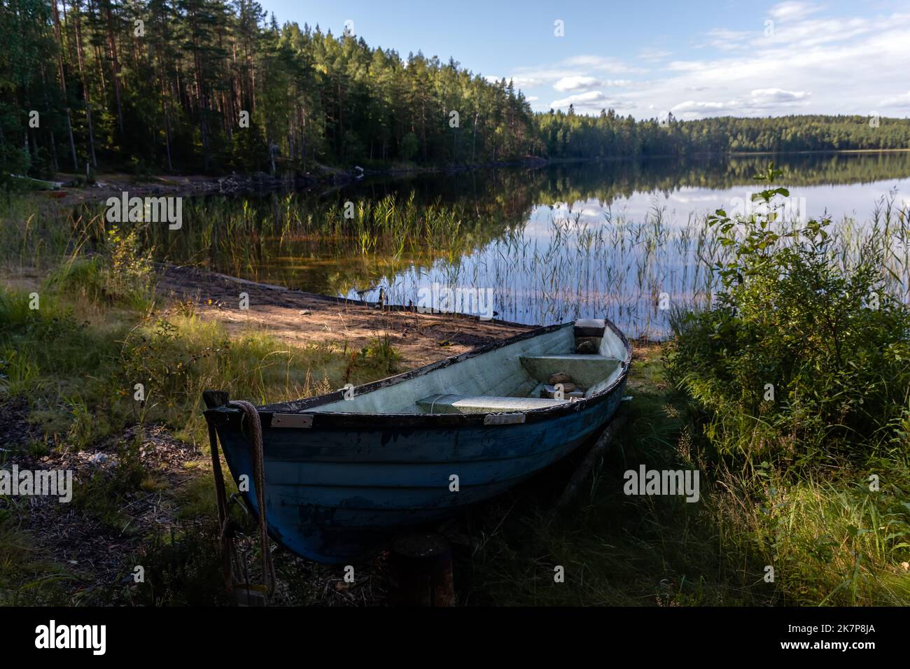 Vecchia barca blu in vetroresina sulla spiaggia sabbiosa nel Parco Nazionale di Repovesi, Finlandia Foto Stock