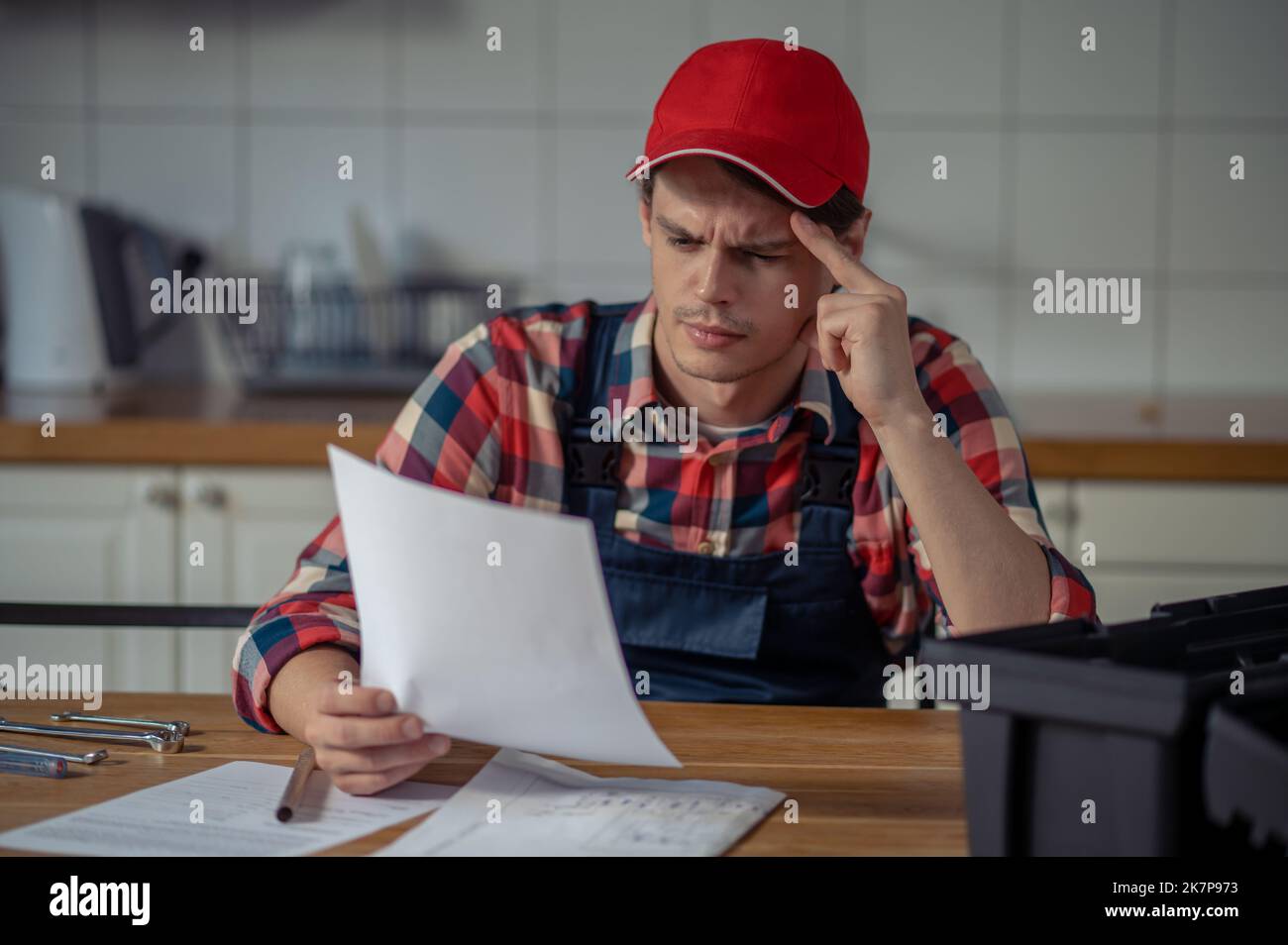 Addetto alla manutenzione attento vestito di indumenti da lavoro per seguire le istruzioni di installazione Foto Stock