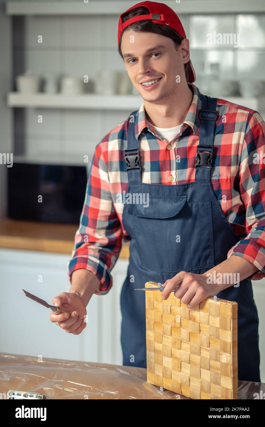 Sorridendo con un paio di attrezzi da carpenteria al lavoro Foto Stock