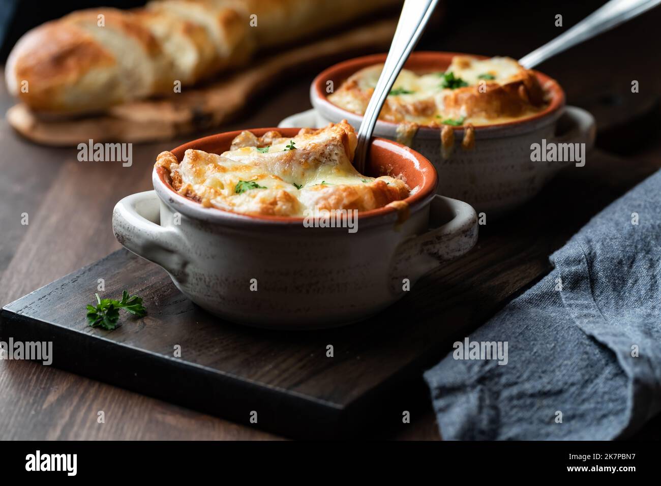 Due cazzi di zuppa ripieni di cipolla francese ricoperti di pane croccante e formaggio fuso. Foto Stock