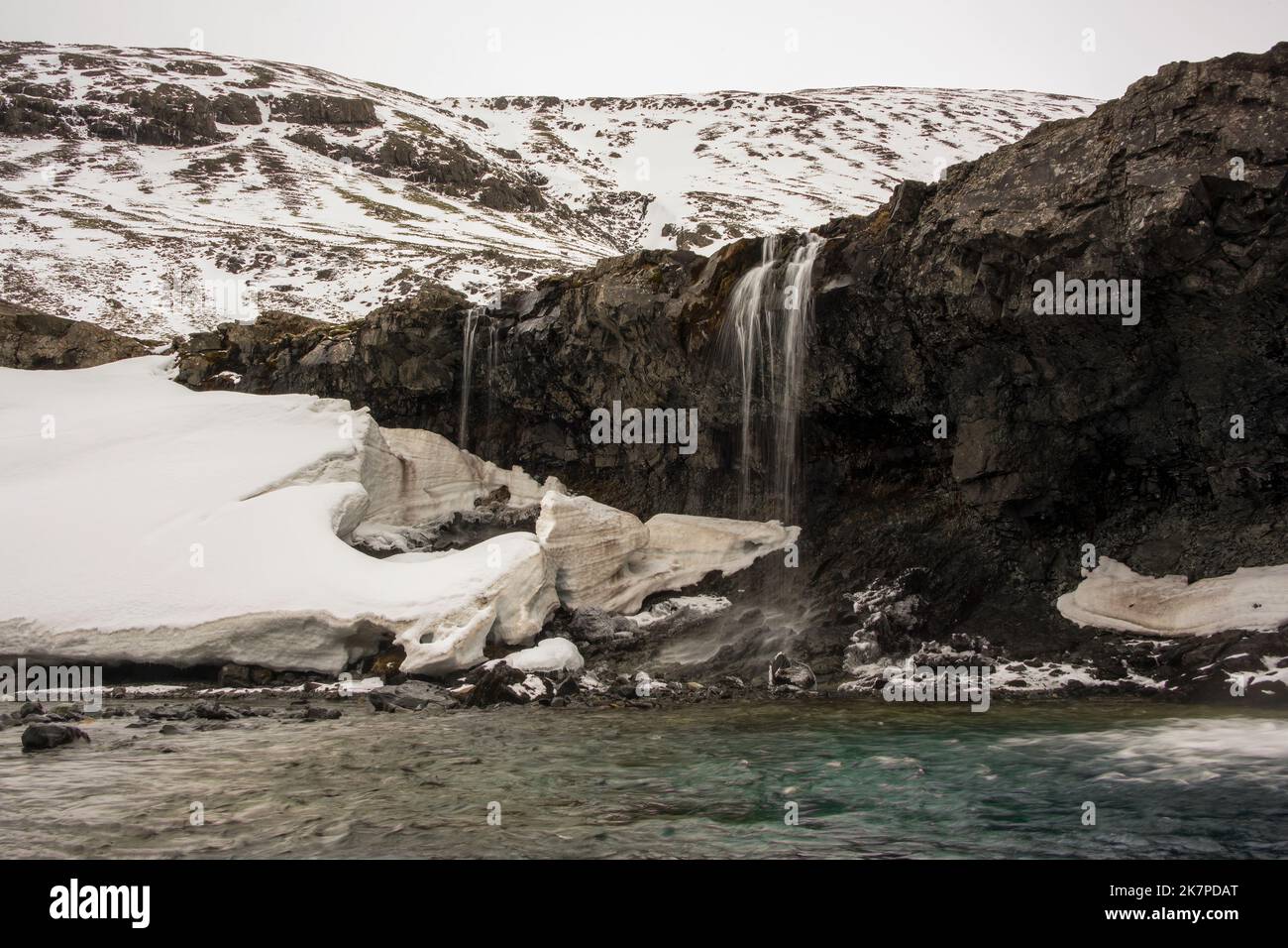 L'acqua ha scolpito la neve alle cascate di Kvernufoss, fiume di Kverna, Islanda Foto Stock