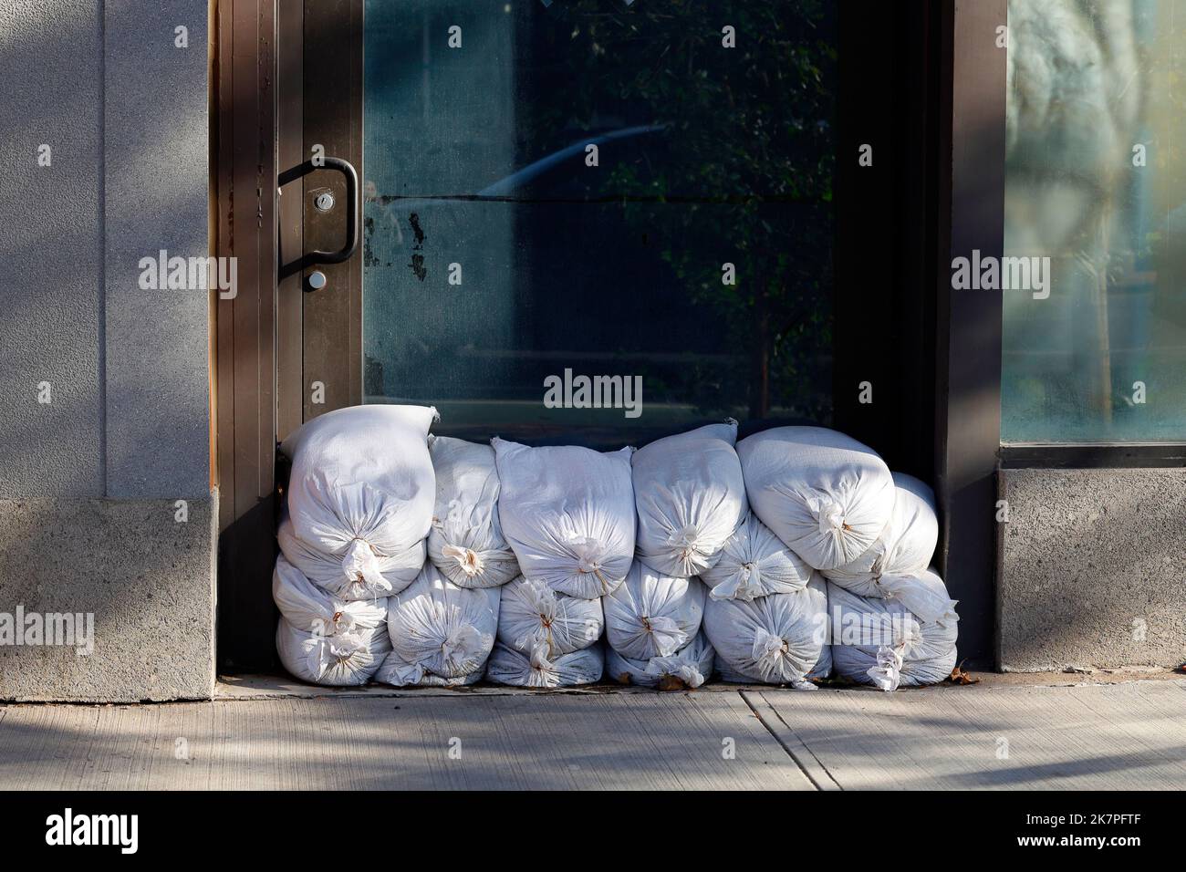 Un mucchio di sacchi di sabbia accatastati contro una porta come misura di prevenzione delle alluvioni. Foto Stock
