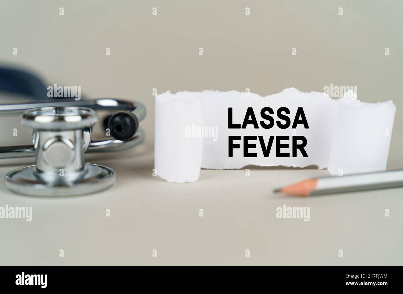 Concetto medico. Su sfondo grigio, uno stetoscopio, una matita e un foglio di carta con l'iscrizione - febbre di Lassa Foto Stock