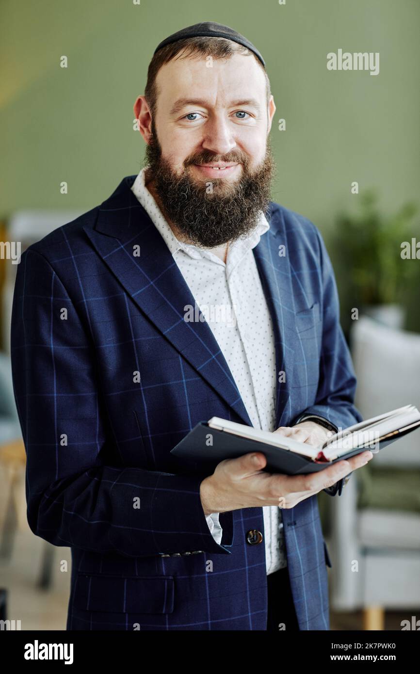 Ritratto verticale dell'uomo ebreo bearded che indossa kippah e guarda la macchina fotografica che tiene il libro Foto Stock