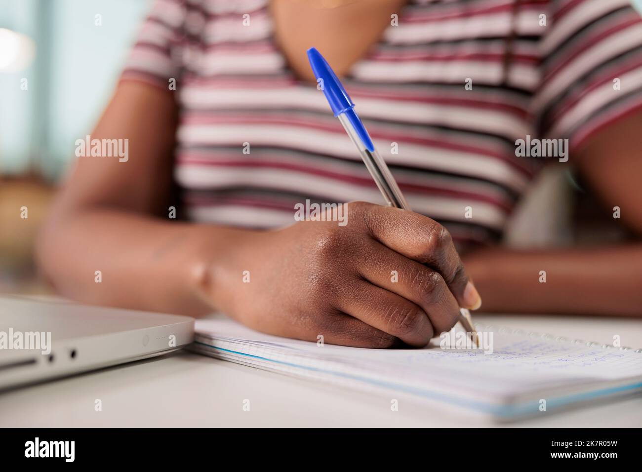 Studente che prende appunti in primo piano notebook, adolescente che studia online con notebook. Donna scrittura a mano con penna in blocco note vista ravvicinata, preparazione per l'esame dei corsi su Internet, facendo compiti a casa Foto Stock