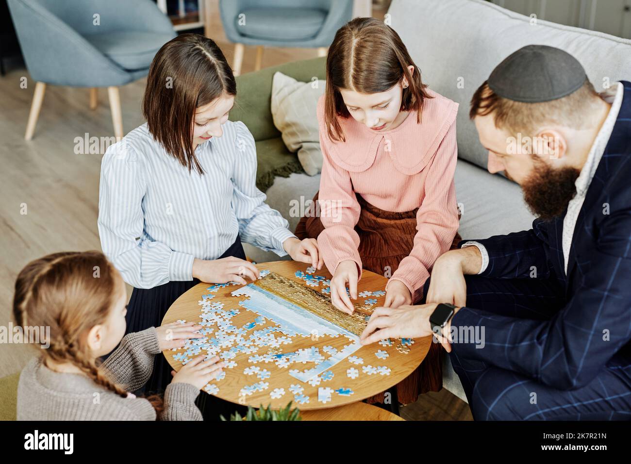 Vista ad alto angolo alla famiglia ebraica che gioca a puzzle insieme a casa Foto Stock