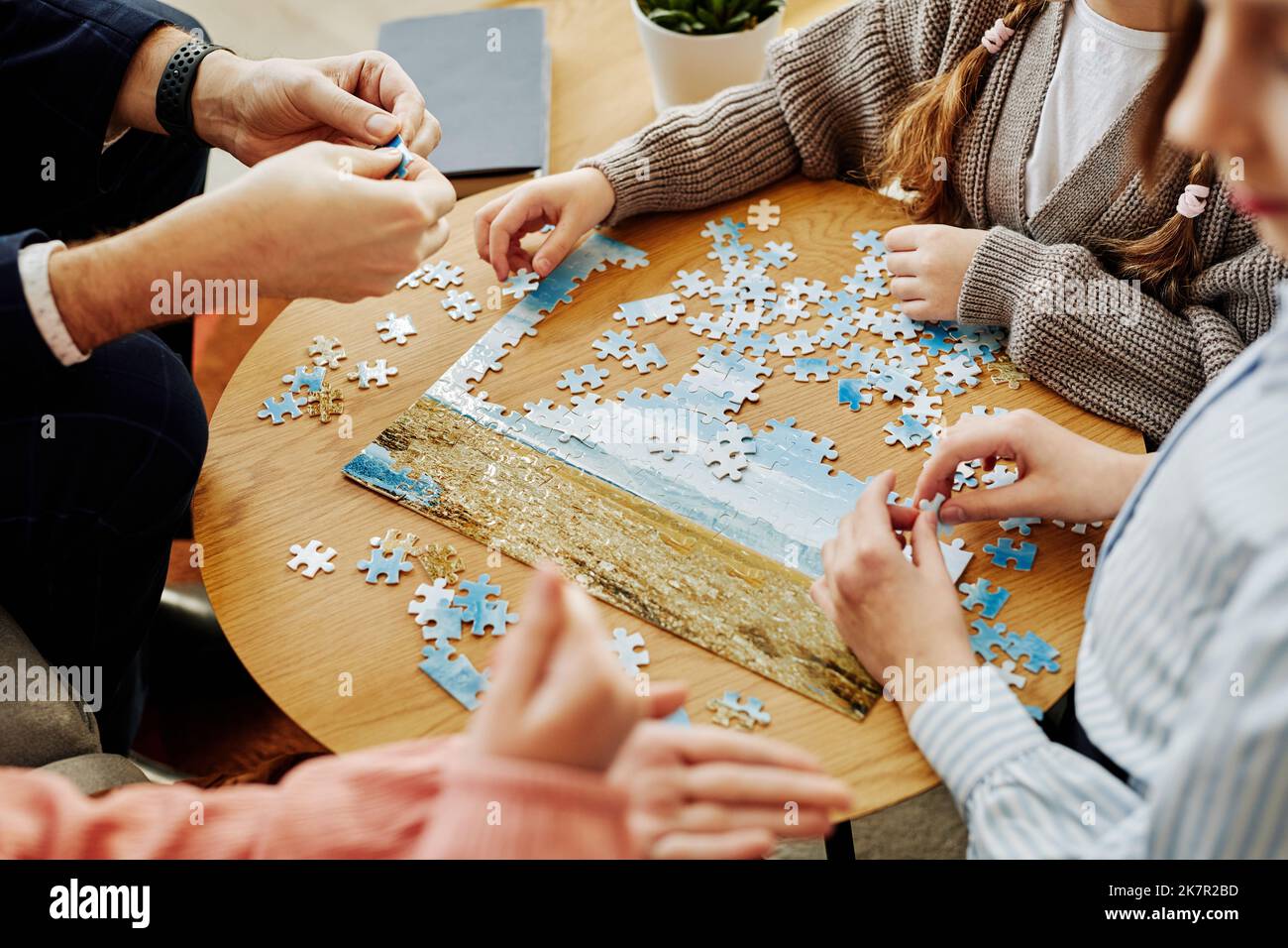 Primo piano di famiglia irriconoscibile giocare a puzzle gioco insieme a casa Foto Stock
