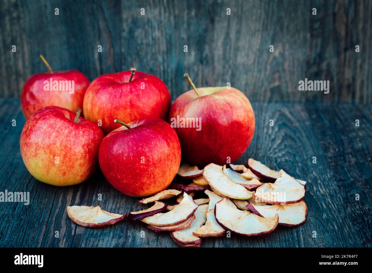 Mele, mele secche e fianchi di rosa giacciono su una tavola di legno scuro Autunno Foto Stock