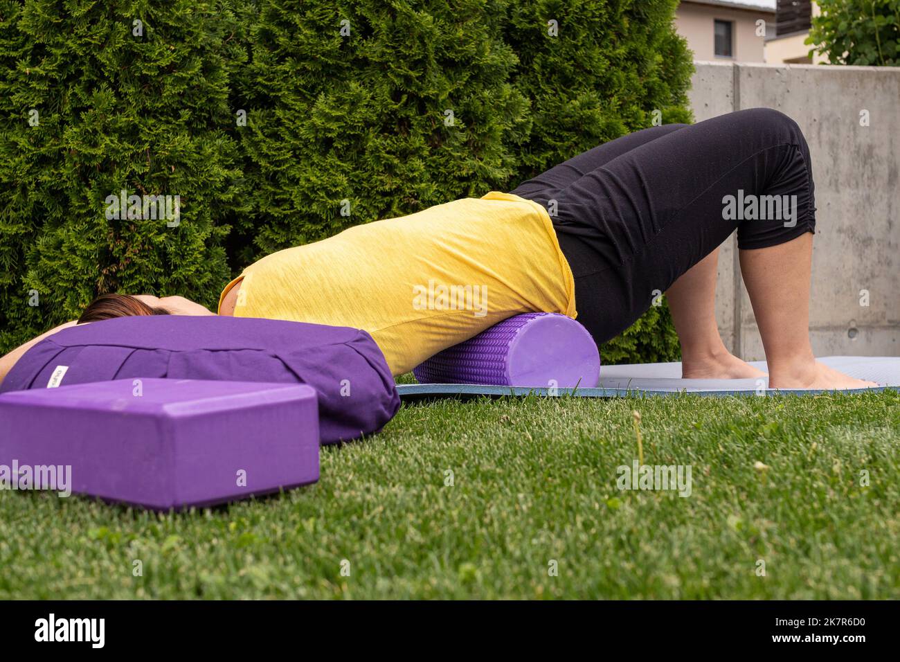Donna che impara a praticare yoga sdraiato su una stuoia facendo asana per i principianti su un prato in estate Foto Stock