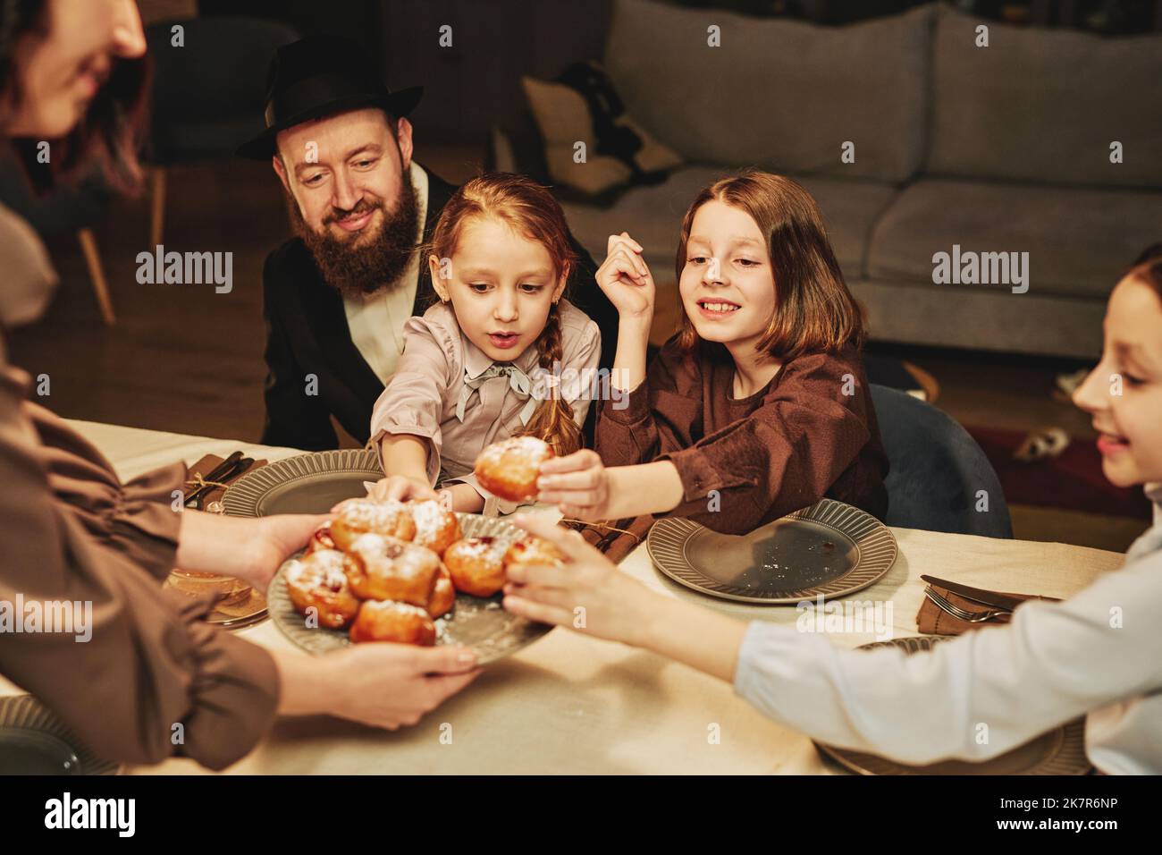 Ritratto della famiglia ebraica ortodossa con i bambini che gustano dolci fatti in casa al tavolo da pranzo Foto Stock