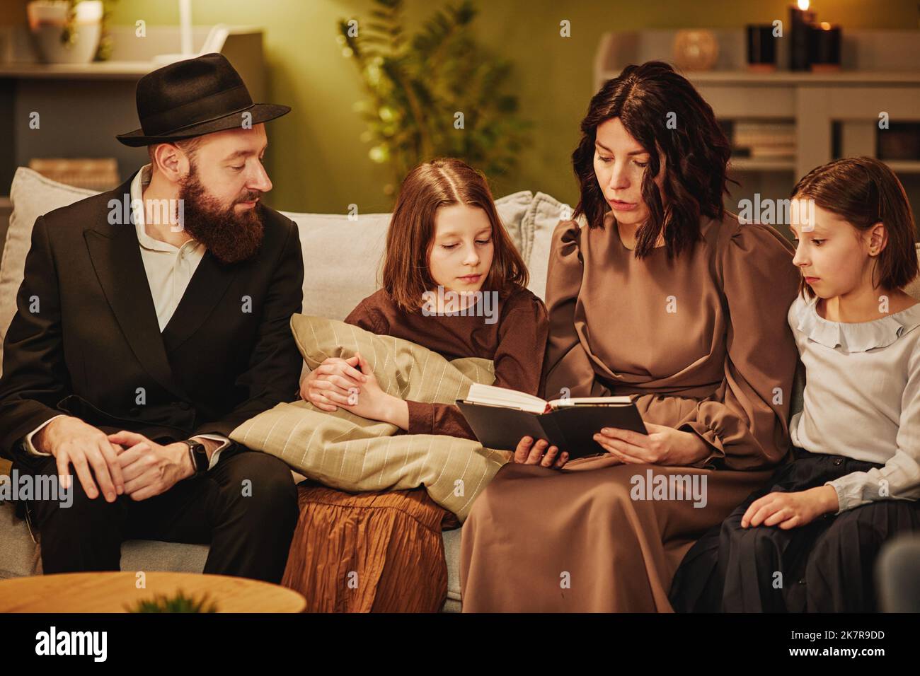 Ritratto della famiglia ebraica tradizionale a casa con focalizzazione sul libro di lettura della madre Foto Stock