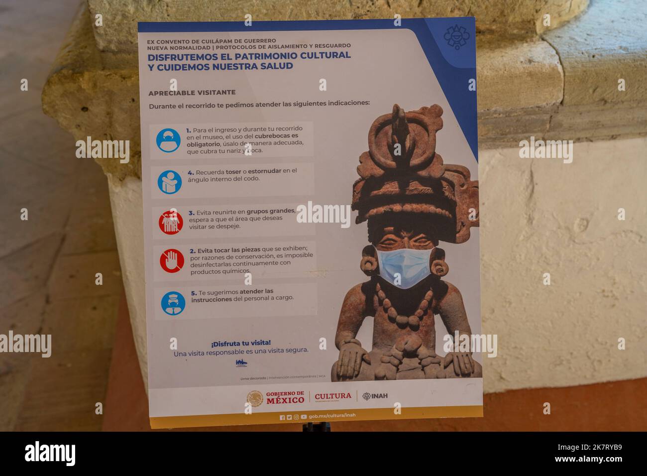 Un cartello informativo COVID raffigurante un manufatto preispanico con maschera, presso l'antica chiesa senza tetto di Cuilapan de Guerrero, una chiesa e un monastero Foto Stock