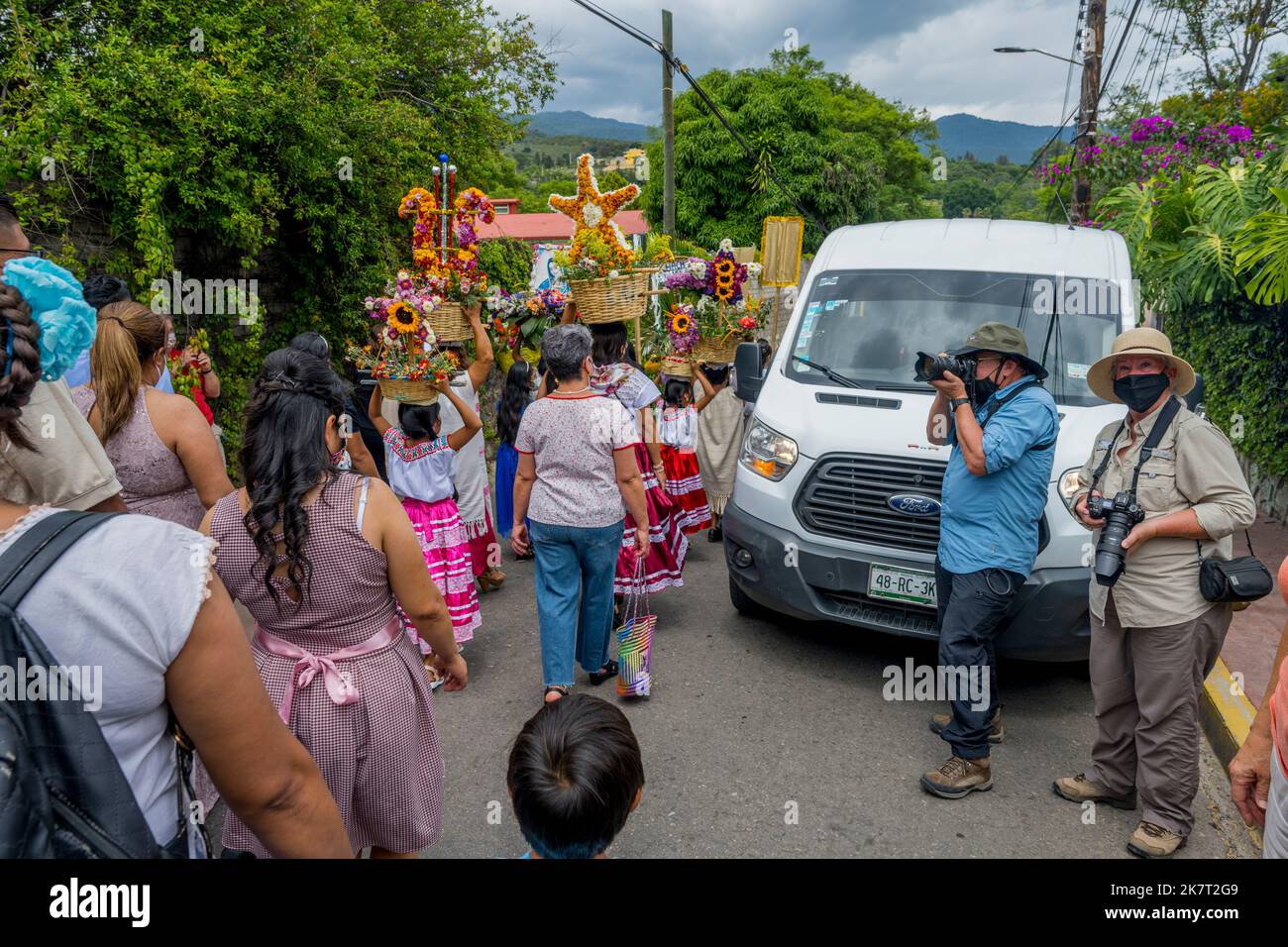 Turisti che fotografano una processione di nozze nella strada della piccola città di San Agustin Etla vicino a Oaxaca, Messico. Foto Stock