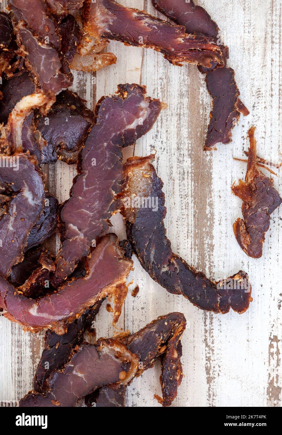 Affettato tradizionale biltong sudafricano o carne curata su superficie rustica di legno bianco Foto Stock