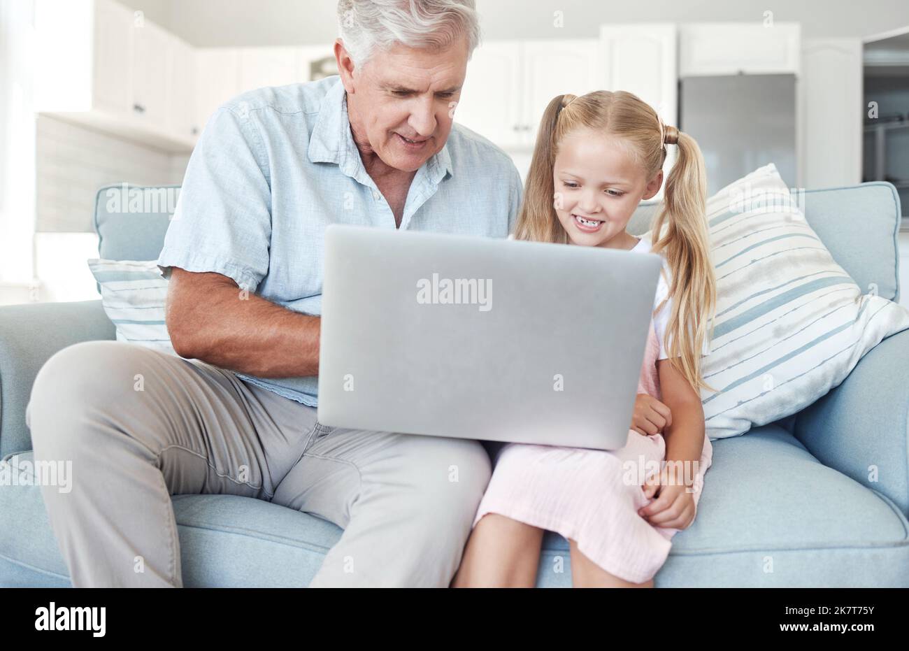 Nonno, ragazza e bambino con notebook sul divano per l'istruzione, l'apprendimento o il gioco insieme su Internet a casa. Senior, uomo e bambino sul divano con Foto Stock