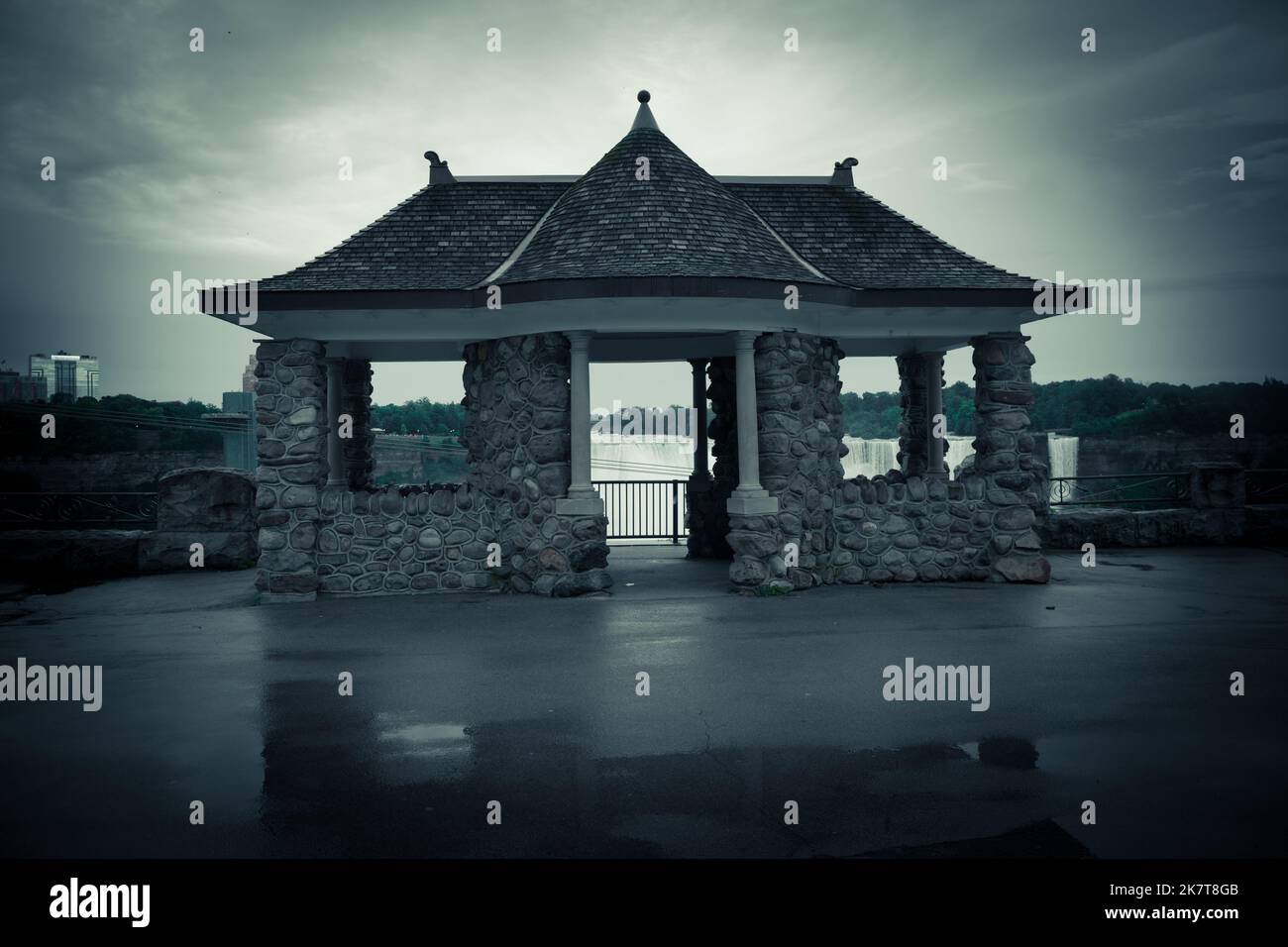 Dettagli architettonici - Gazebo fatto di pietra in stile orientale dietro la quale si trova una cascata. Tono drammatico, scena mistica. Foto Stock