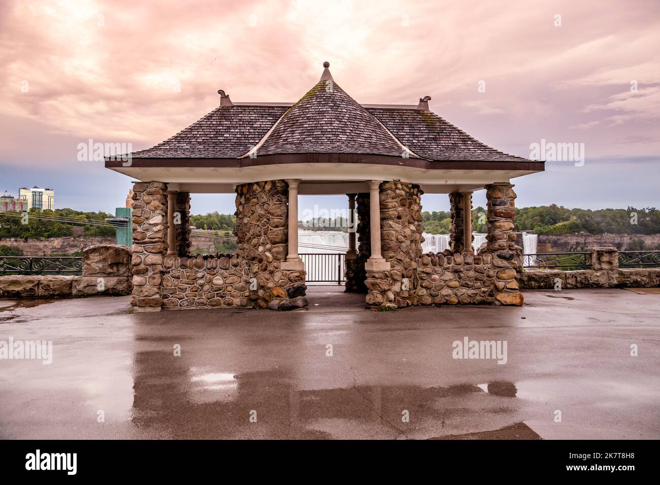Dettagli architettonici - Gazebo fatto di pietra in stile orientale dietro la quale si trova una cascata. Tono drammatico, scena mistica. Foto Stock