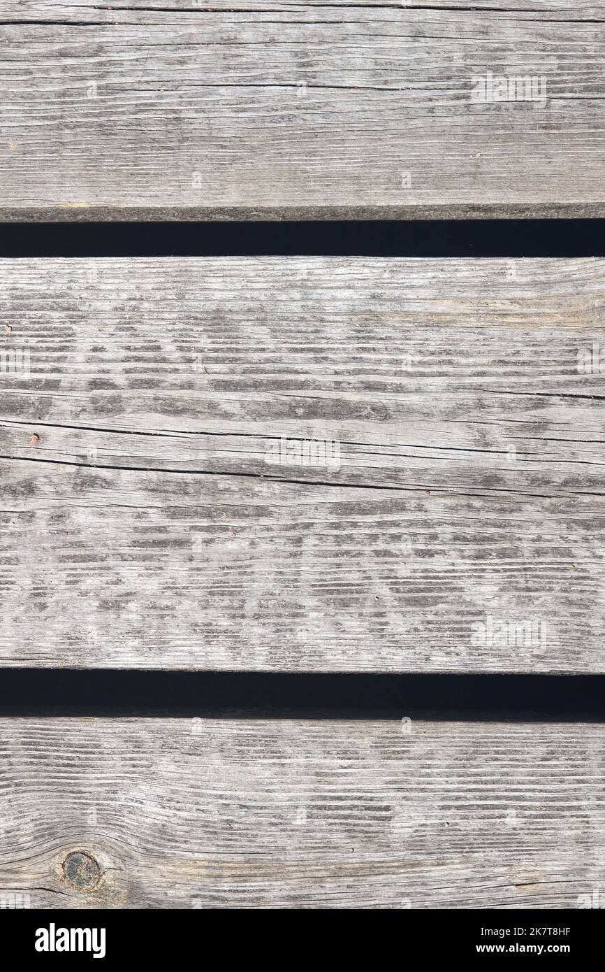 Pavimentazione in legno invecchiato, parete con nodi, crepe e sabbia. Scatto verticale. Foto Stock