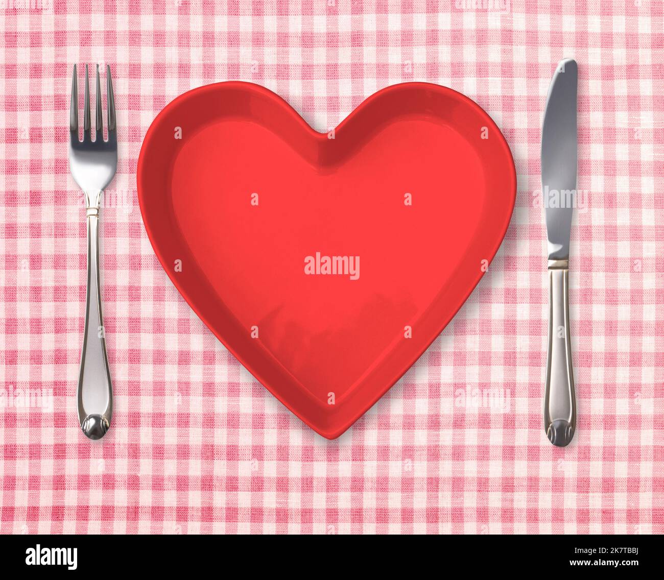 Appuntamenti al tavolo con piatto a forma di cuore. Dima con piastra vuota, forchetta, coltello su tovaglia retrò. Foto Stock