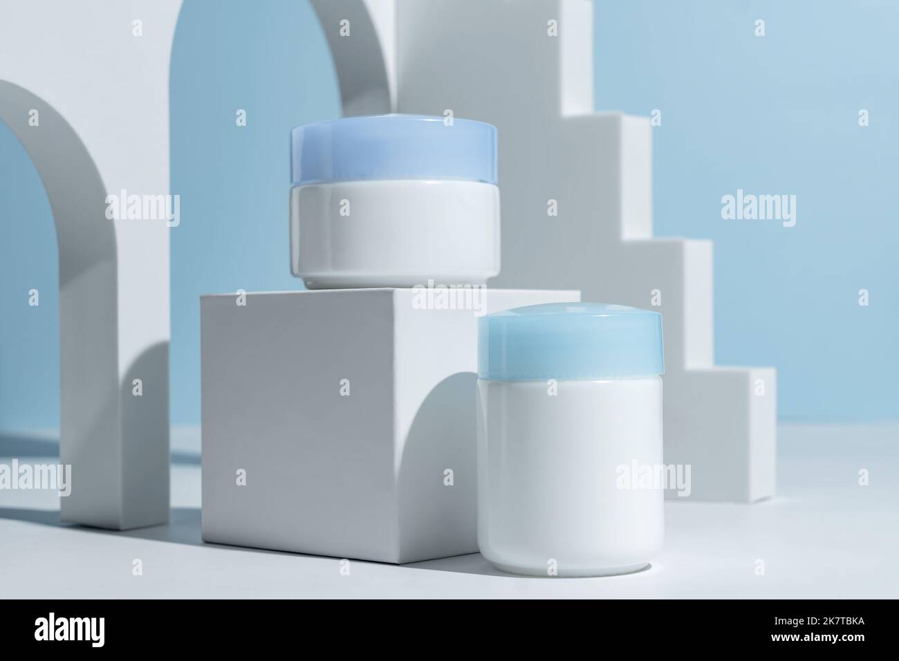 Set di cosmetici naturali per la cura del viso giorno e notte crema su sfondo blu decorato trendy podio e arco. Presentazione cosmetici per la cura della pelle. Simulazione Foto Stock