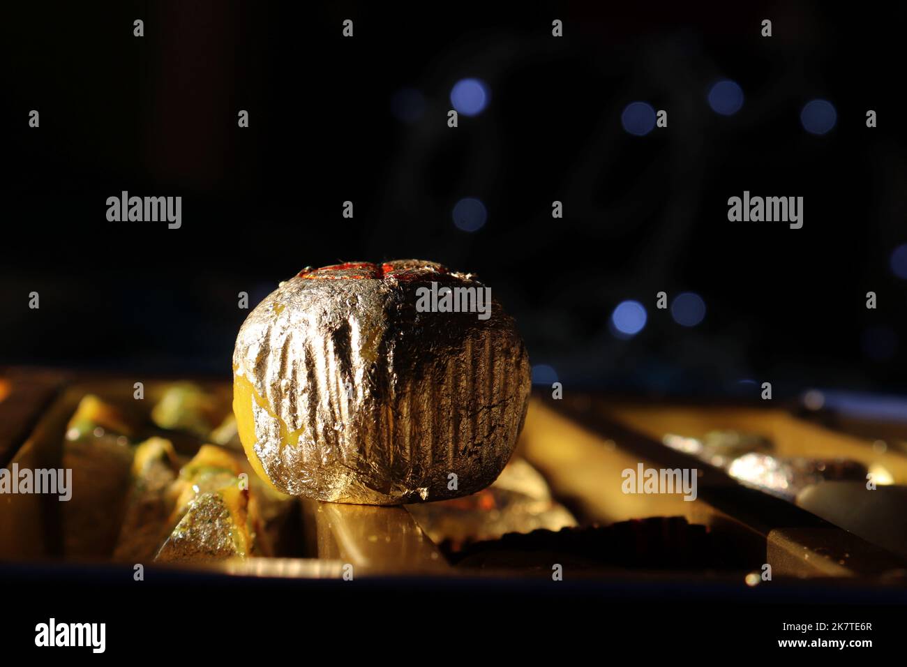 Primo piano di un singolo dolce indiano in un piatto di terracotta/argilla contro il festival bokeh-Diwali/Deepavali Foto Stock