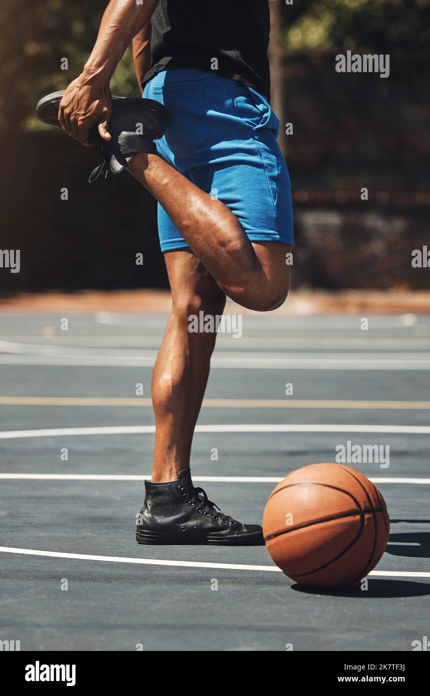 Fitness, basket e gambe stretching uomo sul campo all'aperto per la preparazione muscolare con allenamento. Muscoloso, forte e maschio atleta con piedi caldi Foto Stock