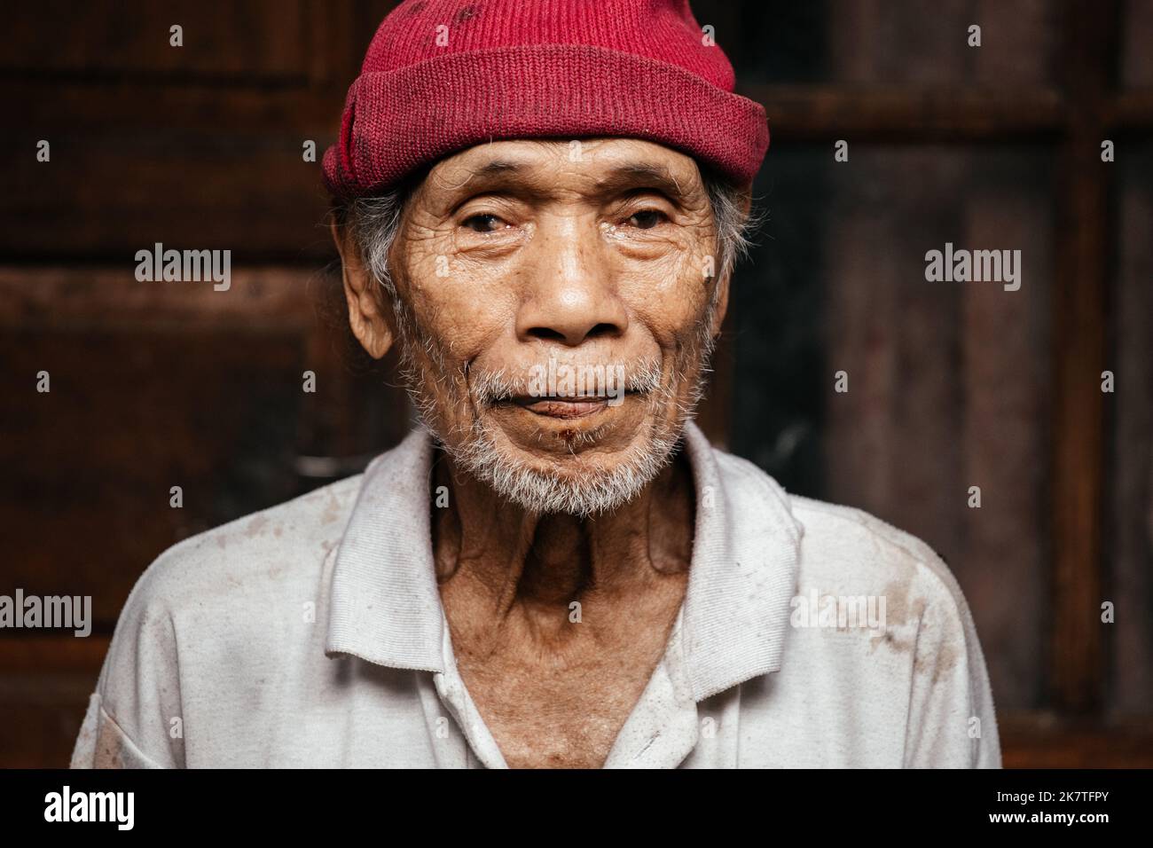 Ritratto di un vecchio balinese in un vecchio maglione e cappello. Indonesia, Bali, 5 settembre 2022. Foto Stock