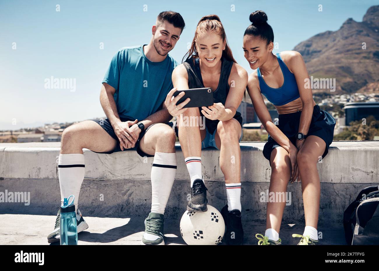 Sport, social media e amici con il telefono e rilassarsi dopo l'allenamento di calcio, fitness e allenamento. Estate, internet e tecnologia con l'atleta e. Foto Stock