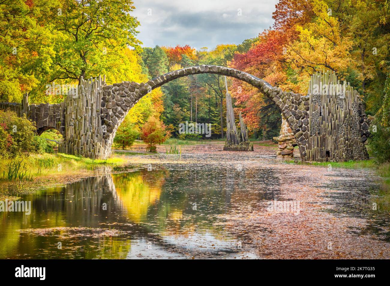 Ponte Rakotzbrucke circondato da alberi gialli autunnali nel Parco Rododendron Kromlau, Sassonia, Germania Foto Stock