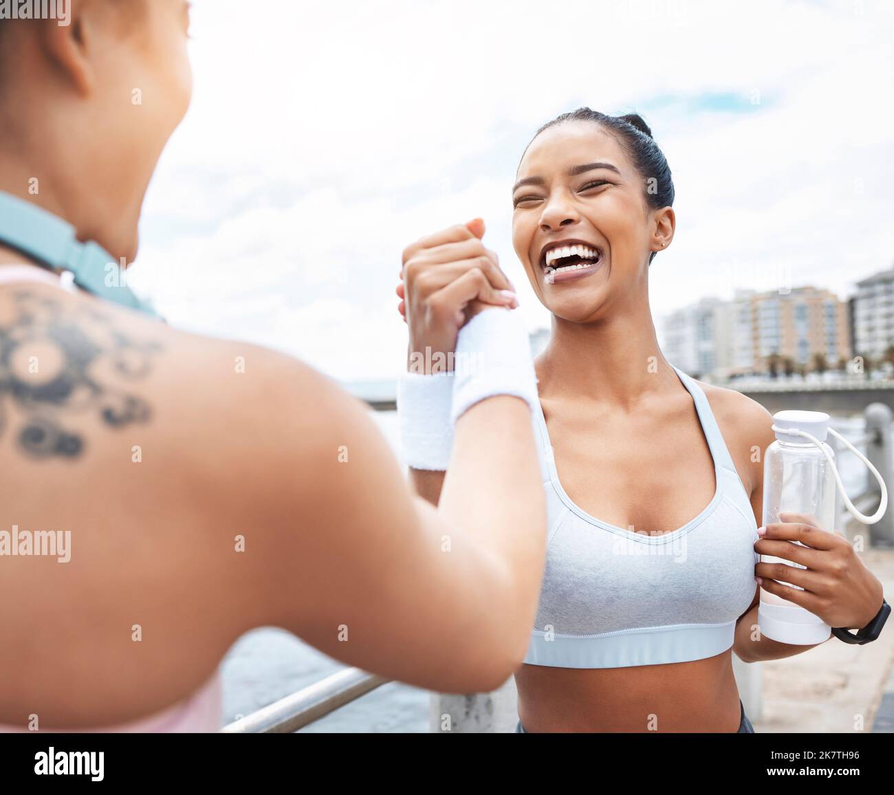 Handshake, donne e vincitrice di allenamento fitness per la competizione di corsa in città strada. Ragazze felici, sorridenti e di sostegno dopo il successo Foto Stock