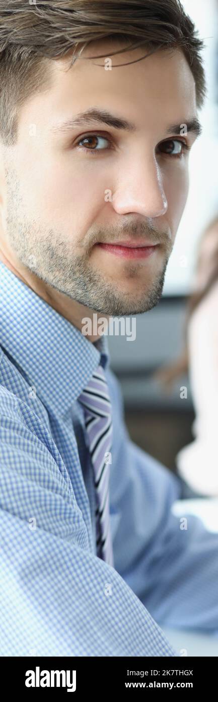 Un dipendente aziendale concentrato sul posto di lavoro guarda in macchina con una collega Foto Stock
