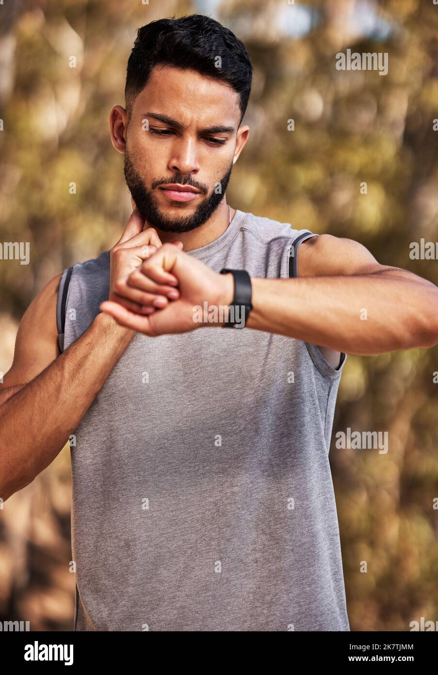 Il mio cuore funziona più di me. un bel giovane che si alza da solo fuori e usa il suo orologio per temporizzare il suo polso dopo una corsa. Foto Stock