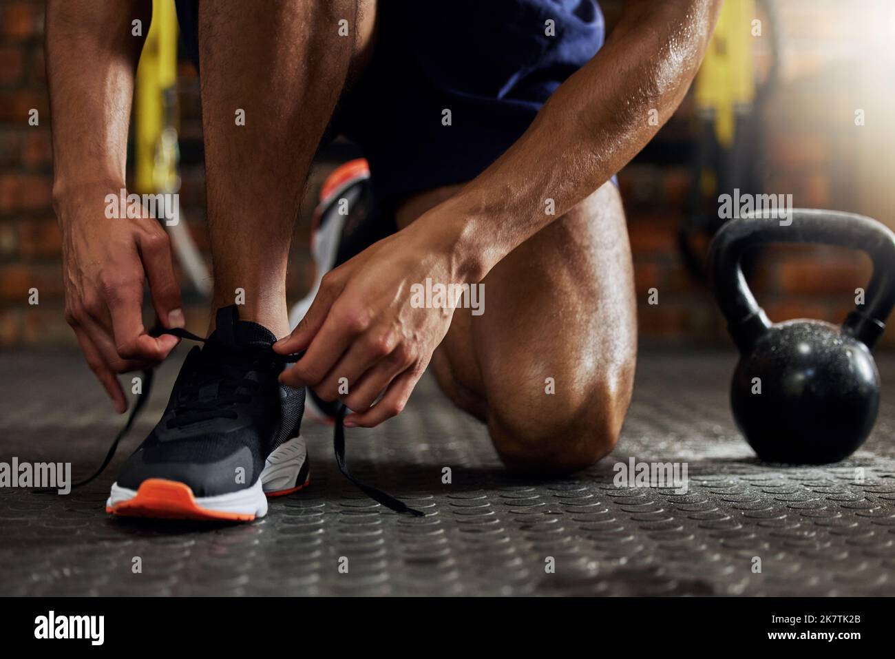 Il successo comincia con autodisciplina. un uomo irriconoscibile che legava le scarpe prima di allenarsi in palestra. Foto Stock