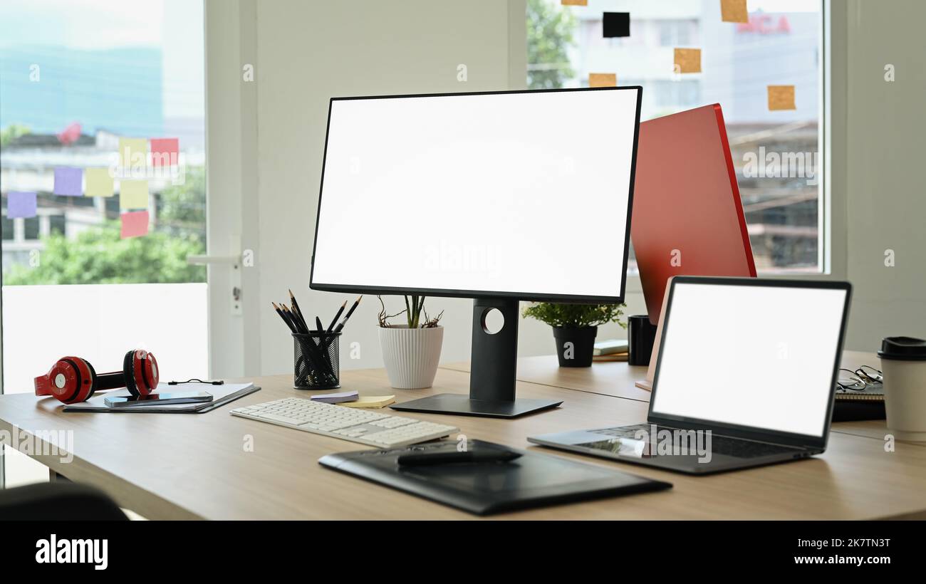 Interni creativi per ufficio con computer portatile, computer con schermo vuoto, tablet grafico e cancelleria su tavolo di legno Foto Stock