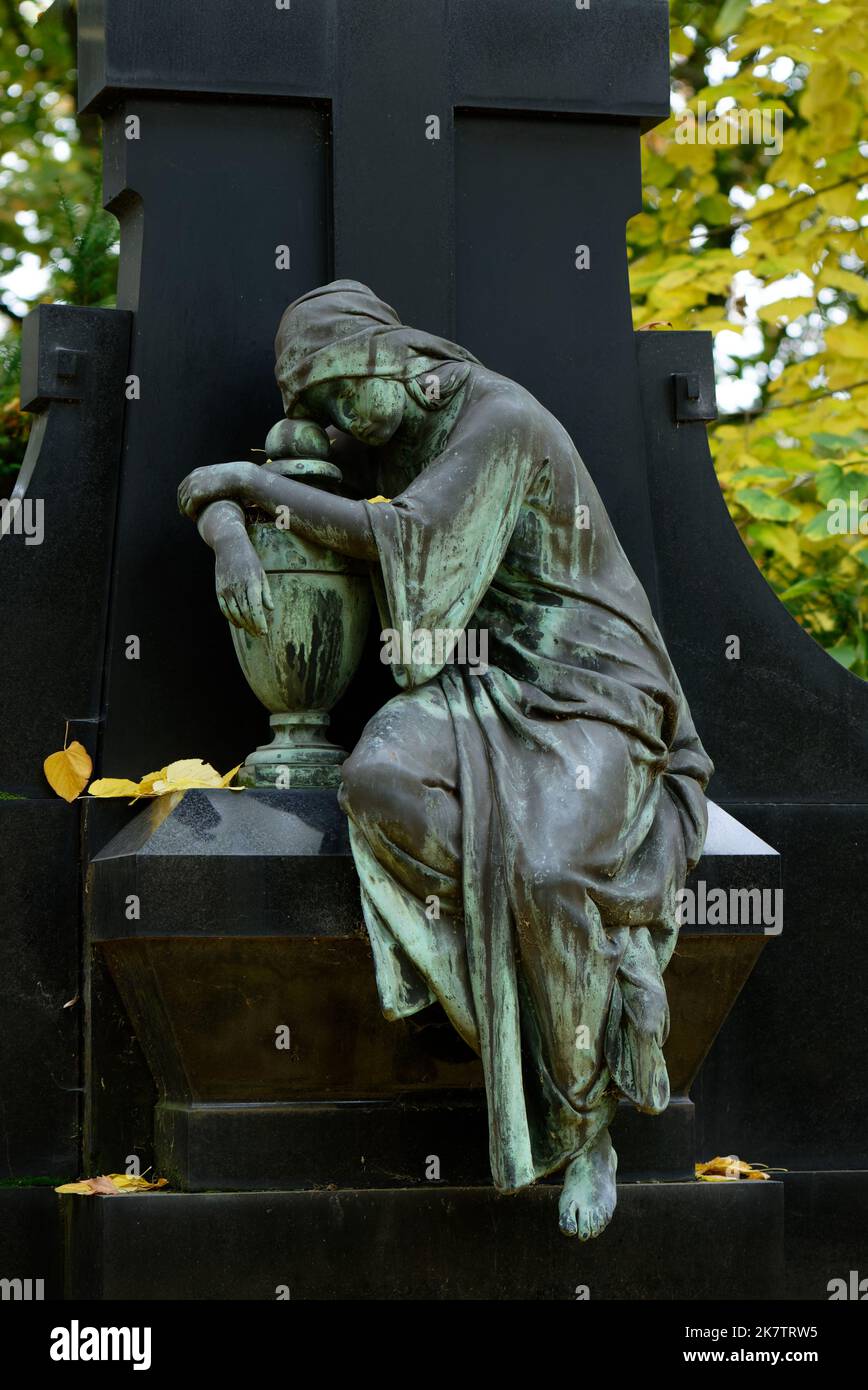 la scultura femminile triste in uno storico cimitero autunnale abbraccia un'urna Foto Stock