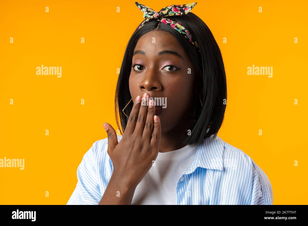 Stordito africano femmina con bocca aperta realizza cattive notizie su sfondo giallo Foto Stock