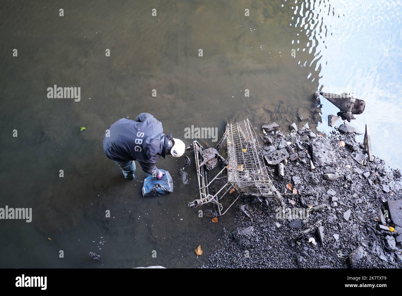 19 ottobre 2022, Amburgo: Un dipendente dell'Ufficio statale per le strade, ponti e corsi d'acqua colloca oggetti trovati in una Alsterfleet quasi vuota sul muro del molo per la rimozione. L'Alsterfleet è stato scaricato per l'ispezione e la pulizia. Il traffico marittimo è stato sospeso su Alsterfleet, Bleichenfleet, Mönkedammfleet, Neuenwallfleet e Herrengrabenfleet. Foto: Marcus Brandt/dpa Foto Stock