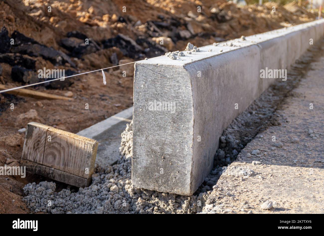 Lavori di installazione di cordoli in cemento in cantiere. Guida a livello di linea stringa. Primo piano. Foto Stock