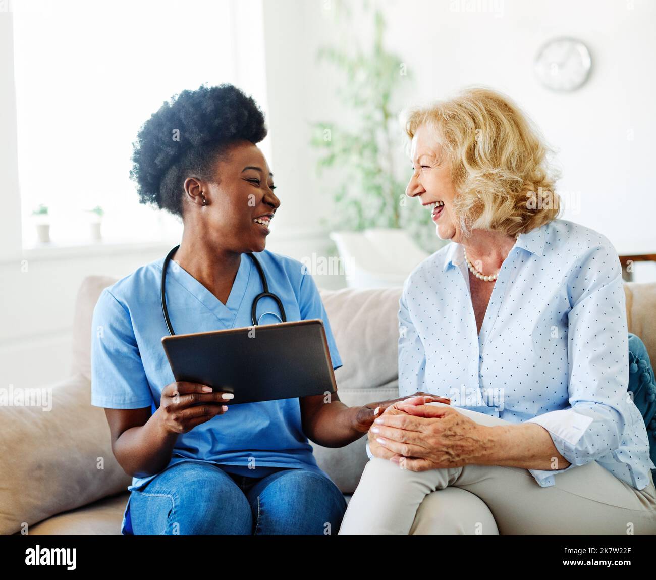 infermiera medico assistenza anziana operatore sanitario aiutare tablet tecnologia pensione casa infermieristica anziana donna salute supporto africano americano nero Foto Stock