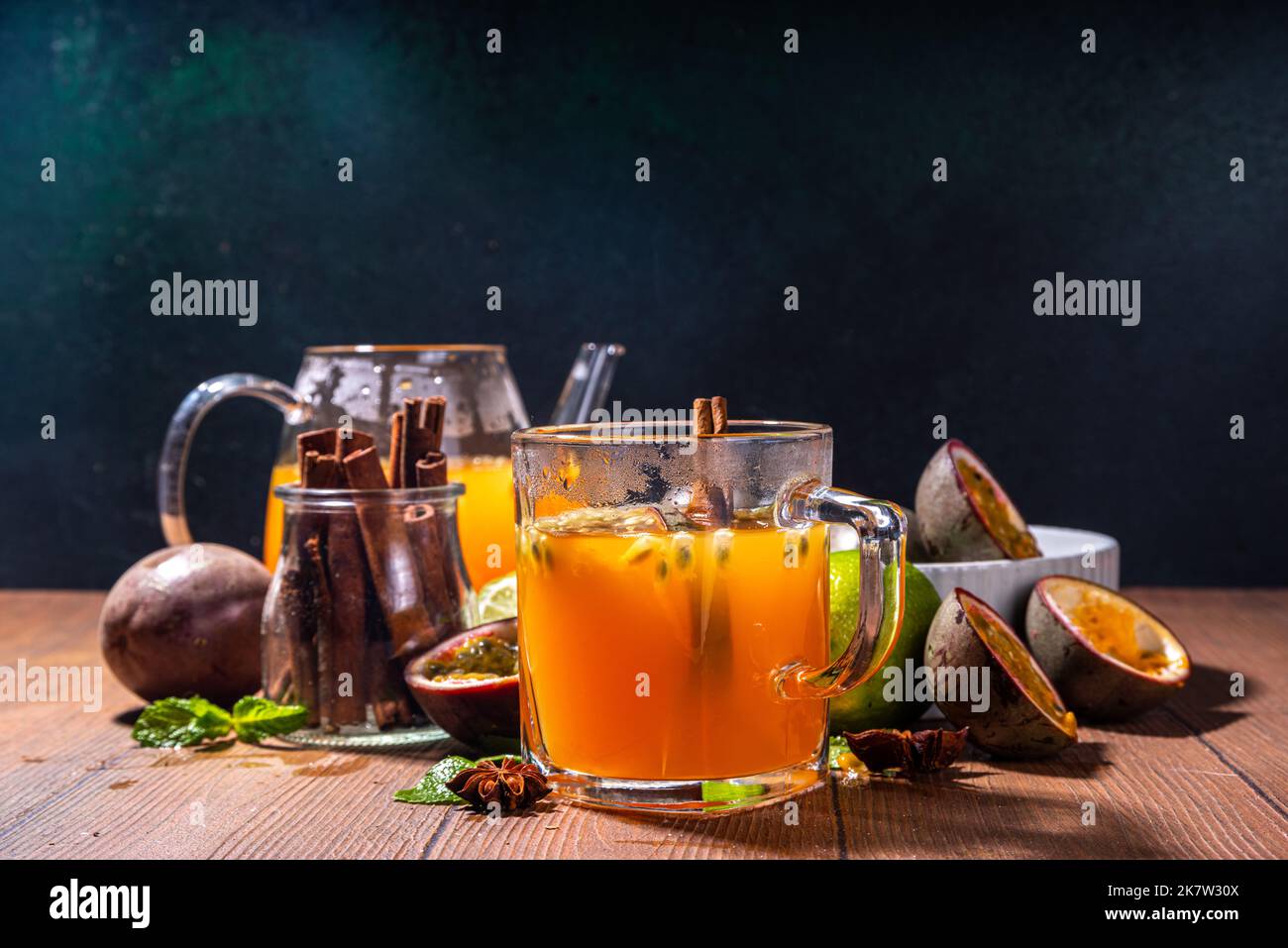 Bevanda a base di tè caldo al frutto della passione con succo di frutta, cannella, lime, su fondo di legno con frutta fresca e spezie Foto Stock