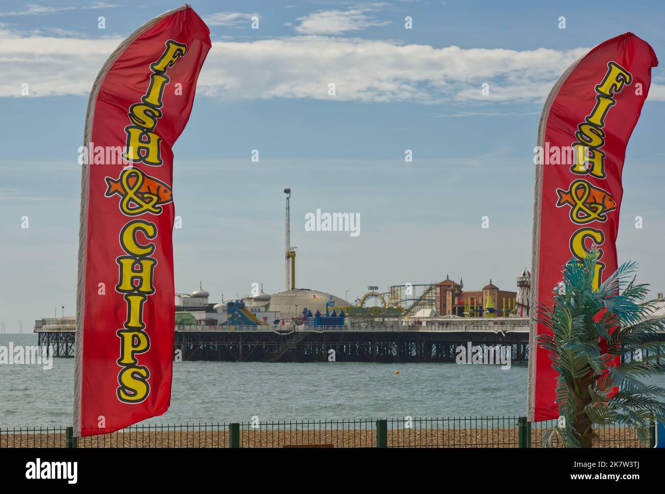 Bandiere che fanno pubblicità a Pesce e patatine fritte sulla spiaggia a Brighton nel Sussex orientale, Inghilterra. Con molo sullo sfondo. Foto Stock